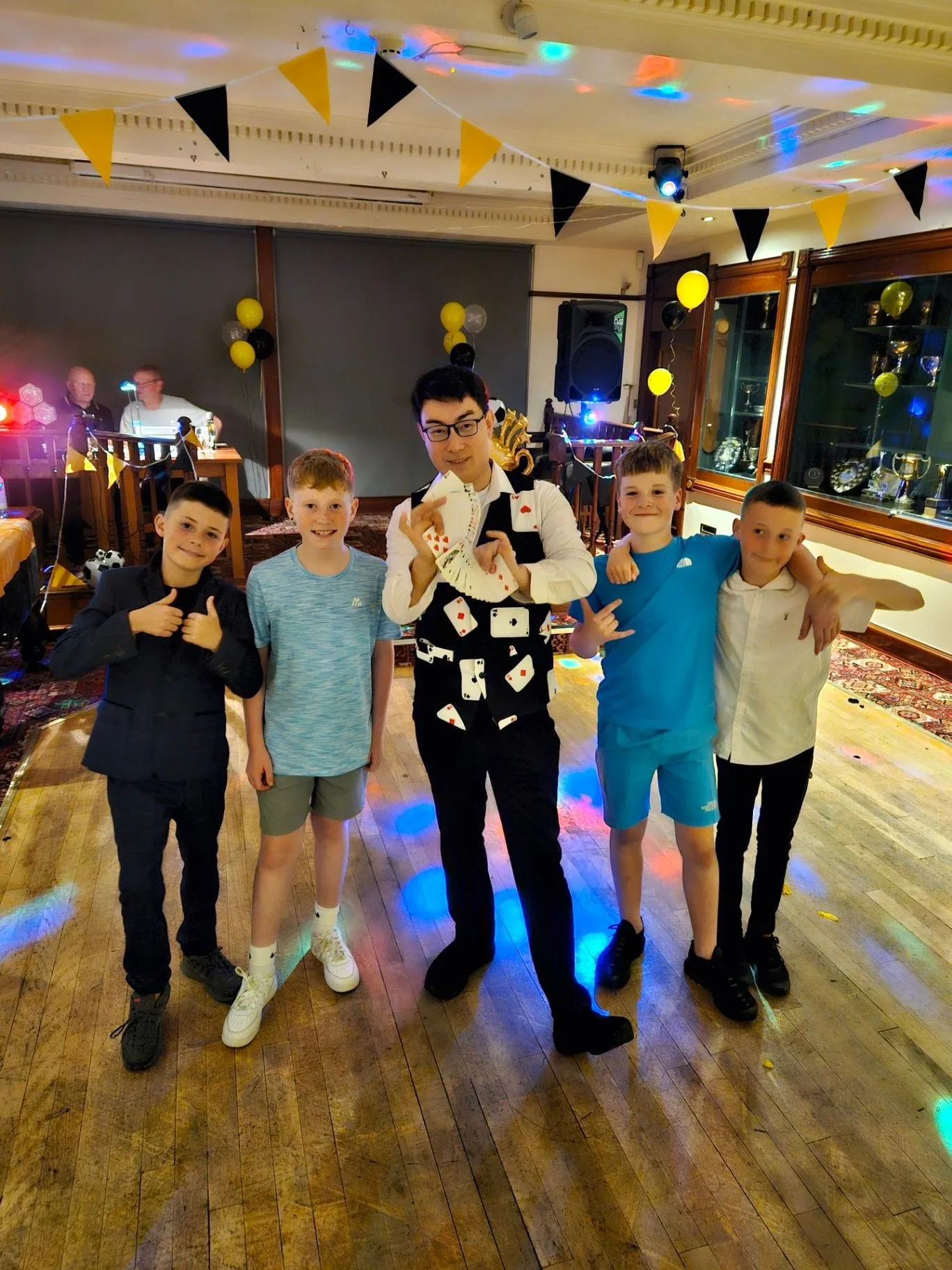 Magic Yin in his playing-card waistcoat performing children's party magic with four boys in Edinburgh
